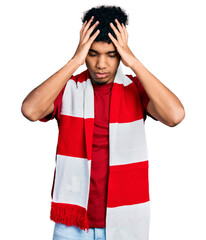 Young african american man football hooligan cheering game suffering from headache desperate and...