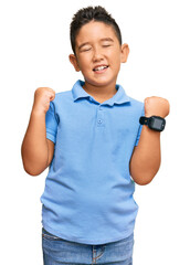 Little boy hispanic kid wearing casual clothes excited for success with arms raised and eyes closed...