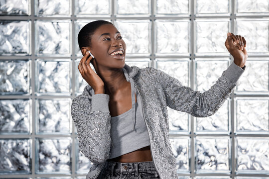 Smiling Black woman dancing and listening to music with wireless earbuds