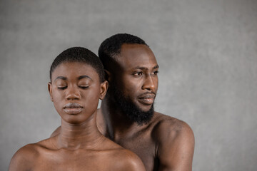 Fototapeta na wymiar Black man embracing girlfriend with closed eyes against gray background
