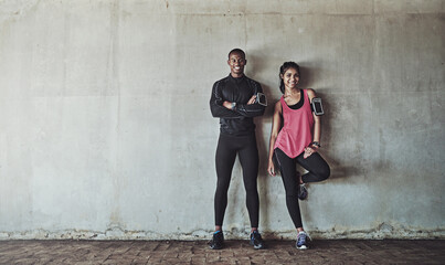 Attaining and maintaining their fitness goals together. Portrait of a sporty young couple exercising together outdoors.