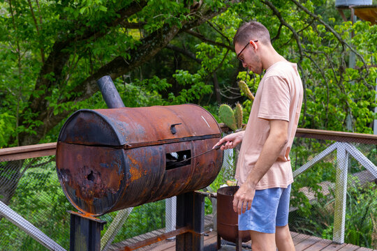 hombre joven caucasico con lentes, realizando una parrillada. 