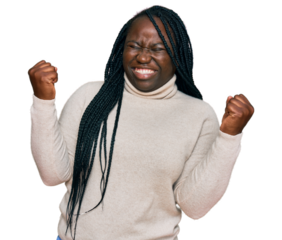 Young black woman with braids wearing casual winter sweater very happy and excited doing winner gesture with arms raised, smiling and screaming for success. celebration concept.