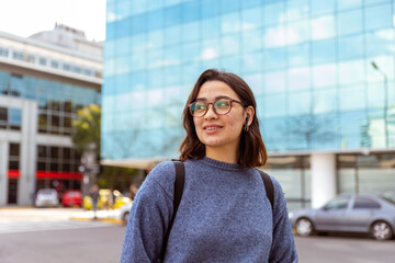 Joven mujer, con mochila, auriculares, preparada para comenzar la universidad. Fotografía plano medio.