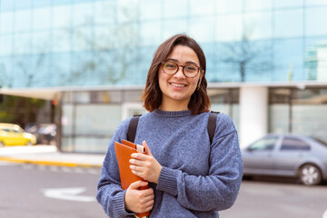 Joven mujer, con mochila, auriculares, preparada para comenzar la universidad. Fotografía plano medio.