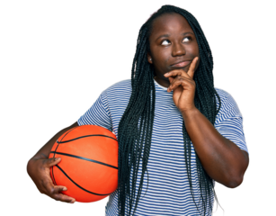 Young black woman with braids holding basketball ball serious face thinking about question with hand on chin, thoughtful about confusing idea