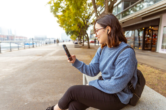 Joven mujer, con mochila, auriculares, usando el celular, telefono. Fotograf&iacute;a plano medio.