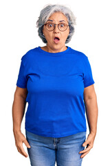 Senior woman with gray hair wearing casual clothes and glasses scared and amazed with open mouth...