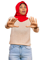 Young african american woman wearing traditional islamic hijab scarf doing stop gesture with hands palms, angry and frustration expression