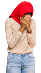 Young african american woman wearing traditional islamic hijab scarf with sad expression covering face with hands while crying. depression concept.