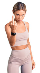 Beautiful caucasian woman wearing sportswear showing middle finger, impolite and rude fuck off expression