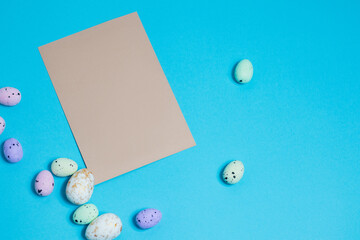 Layout of colorful easter eggs and card on a blue background. Holiday concept with place for text.