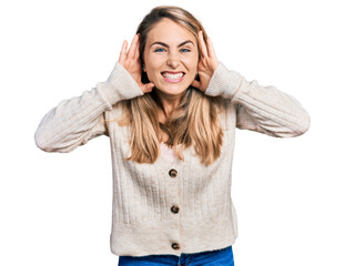 Young blonde woman wearing casual clothes trying to hear both hands on ear gesture, curious for gossip. hearing problem, deaf