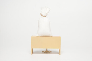 A picture of miniature desk with money bag on white background. Payroll and compensation concept
