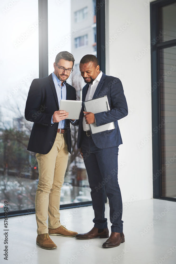 Poster Building their business brand with technology and teamwork. Shot of two businessmen using a digital tablet together at work.