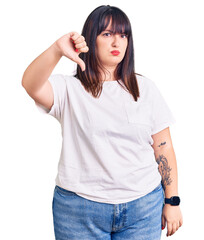 Young plus size woman wearing casual clothes looking unhappy and angry showing rejection and negative with thumbs down gesture. bad expression.
