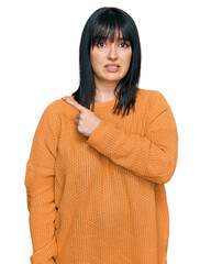 Young hispanic woman wearing casual clothes pointing aside worried and nervous with forefinger,...