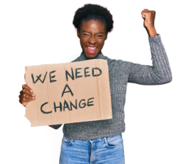 Young african american girl holding we need a change banner screaming proud, celebrating victory and success very excited with raised arms
