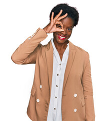 Young african american girl wearing business clothes smiling happy doing ok sign with hand on eye looking through fingers