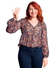 Young beautiful redhead woman wearing casual t-shirt showing and pointing up with fingers number...