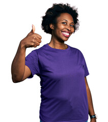 African american woman with afro hair wearing casual purple t shirt doing happy thumbs up gesture...