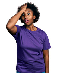 Fototapeta na wymiar African american woman with afro hair wearing casual purple t shirt surprised with hand on head for mistake, remember error. forgot, bad memory concept.