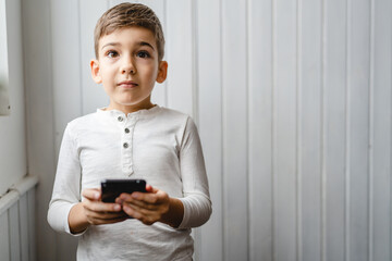 One caucasian boy child use smartphone mobile phone at home play games