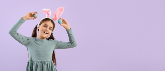 Little girl with bunny ears and Easter eggs on lilac background with space for text