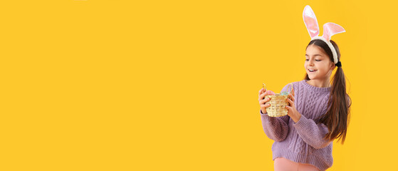 Little girl with bunny ears and Easter basket on yellow background with space for text