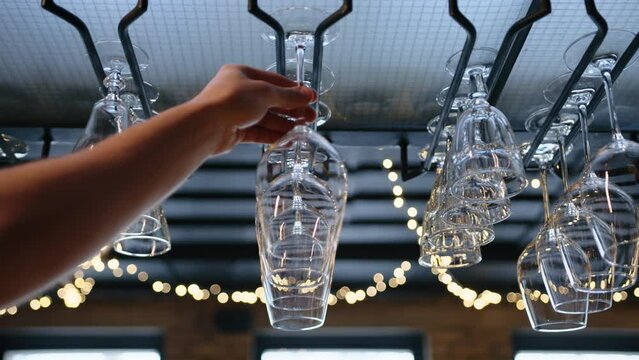 Clean wine glasses hanging upside down a bar rack in restaurant. slow motion. High quality 4k footage