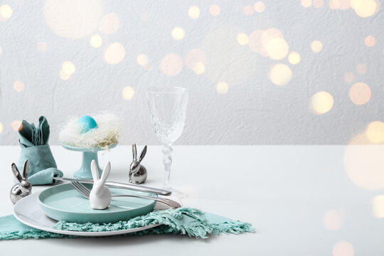 Beautiful table setting for Easter celebration on light background with space for text