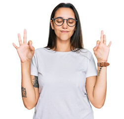Young hispanic woman wearing casual white t shirt relaxed and smiling with eyes closed doing meditation gesture with fingers. yoga concept.