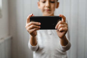 One caucasian boy child use smartphone mobile phone at home play games