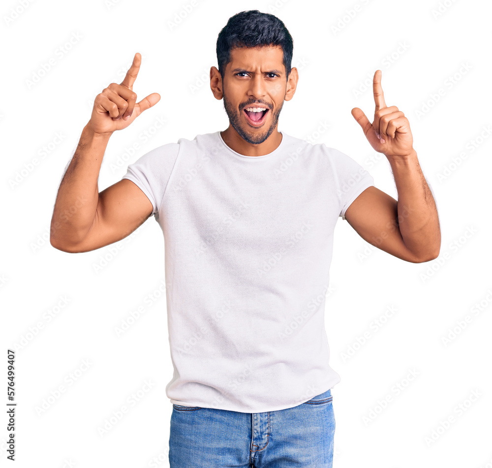 Sticker young latin man wearing casual clothes smiling amazed and surprised and pointing up with fingers and