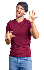 Handsome hispanic man wearing casual clothes smiling funny doing claw gesture as cat, aggressive and sexy expression