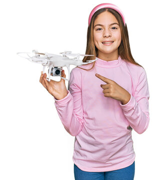 Beautiful brunette little girl using drone smiling happy pointing with hand and finger