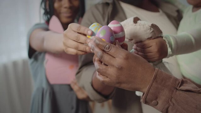 Closeup of African American family members putting colored Easter eggs together while celebrating Easter at home