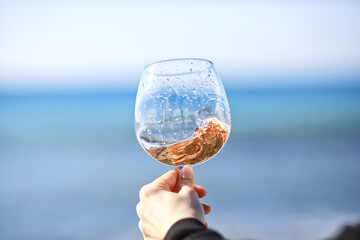 a glass of port wine on the background of the sea, a hand with wine
