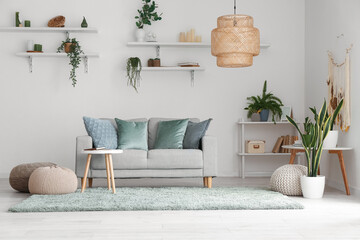 Interior of light living room with green houseplants, sofa and shelves
