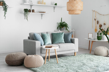 Interior of light living room with green houseplants, sofa and tables