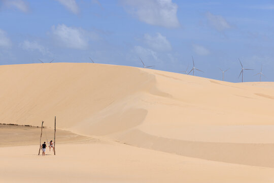 dunas do parque nacional dos Len&ccedil;&oacute;is Maranhenses com capta&ccedil;&atilde;o e&oacute;lica de energia ao fundo 