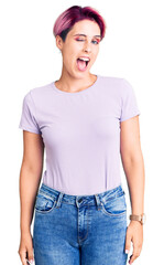 Fototapeta premium Young beautiful woman with pink hair wearing casual clothes winking looking at the camera with sexy expression, cheerful and happy face.