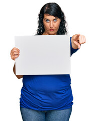 Plus size brunette woman holding blank empty banner celebrating victory with happy smile and winner expression with raised hands