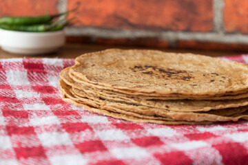 Group of corn tortillas stacked on a cloth napkin, with the background out of focus.