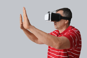 Mature man in VR glasses on light background