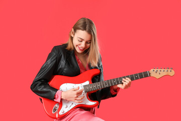 Fototapeta premium Young woman playing guitar on red background