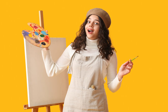 Surprised Teenage Artist With Brush, Paint Palette And Easel On Yellow Background