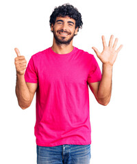 Handsome young man with curly hair and bear wearing casual pink tshirt showing and pointing up with fingers number six while smiling confident and happy.