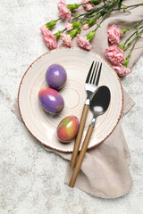 Table setting with Easter eggs, cutlery and carnation flowers on white grunge background