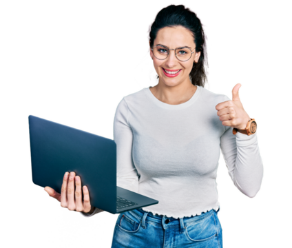 Young hispanic woman working using computer laptop smiling happy and positive, thumb up doing excellent and approval sign - Powered by Adobe